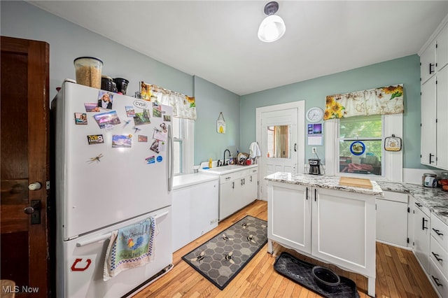 2226 W 13th St, Ashtabula, OH 44004 - kitchen with freestanding refrigerator, light wood-type flooring, a sink, and white cabinetry