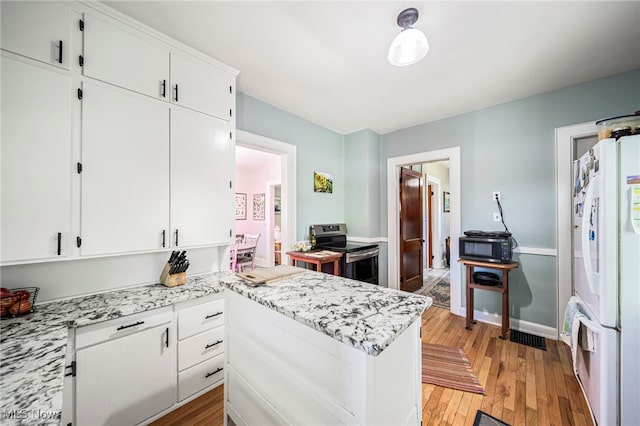 2226 W 13th St, Ashtabula, OH 44004 - kitchen featuring stainless steel range with electric stovetop, estacked washer and dryer, white cabinetry, light wood finished floors, and freestanding refrigerator