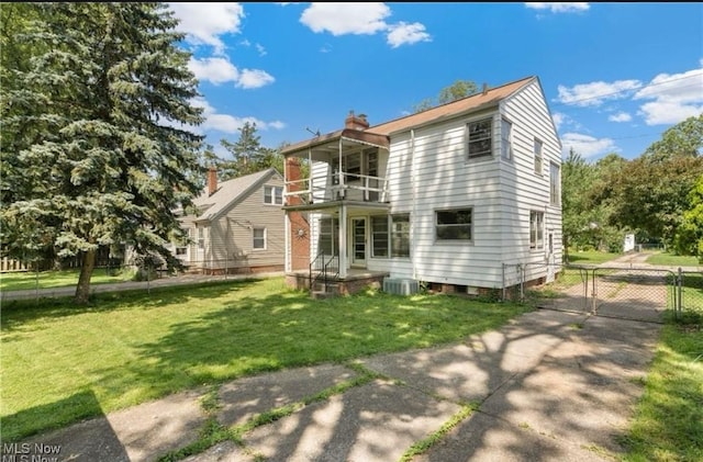 rear view of property featuring a balcony, a gate, a chimney, and central AC