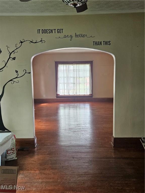 825 Summit St, Salem, OH 44460 - spare room featuring dark wood-type flooring, ornamental molding, a textured ceiling, arched walkways, and baseboards