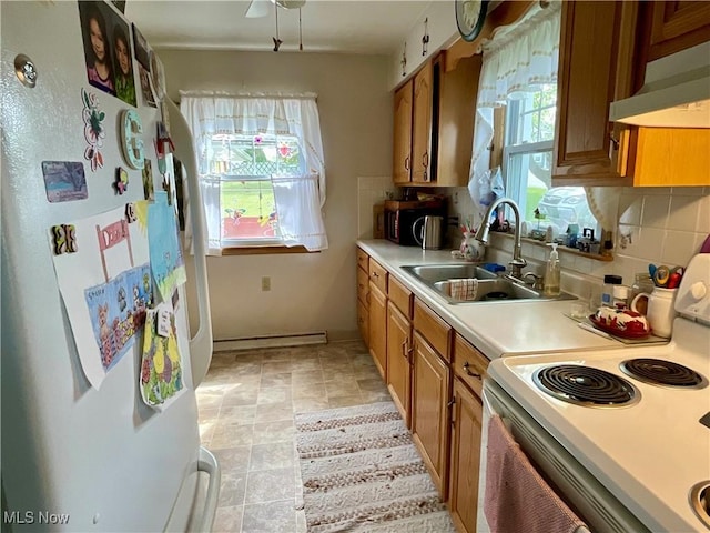 kitchen with white appliances, under cabinet range hood, light countertops, and healthy amount of natural light