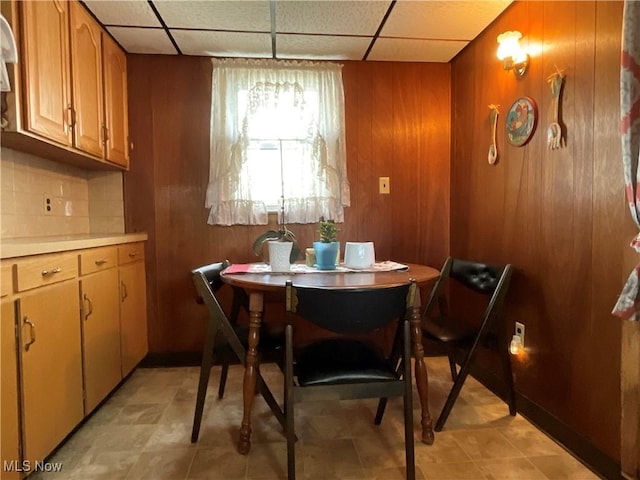 dining room with wooden walls and a drop ceiling