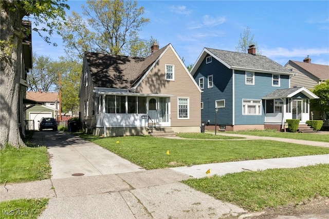 4414 W 171st St, Cleveland, OH 44135 - view of front of house with entry steps, concrete driveway, a front lawn, an outdoor structure, and a sunroom