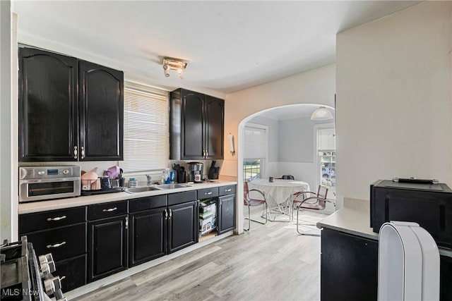 4414 W 171st St, Cleveland, OH 44135 - kitchen with a sink, arched walkways, dark cabinets, light countertops, and light wood-style floors