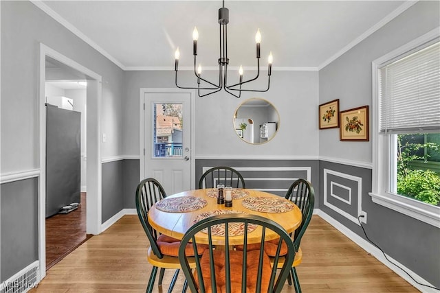 dining area featuring a chandelier, light wood-type flooring, ornamental molding, and baseboards