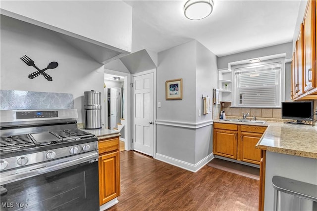 kitchen featuring stainless steel gas stove, a sink, dark wood-style flooring, and brown cabinets