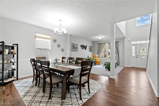 dining space featuring wood finished floors, a chandelier, baseboards, and a textured ceiling