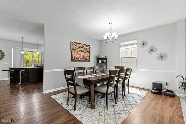 dining space with baseboards, a chandelier, and wood finished floors