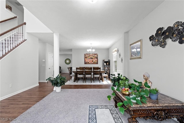 carpeted living area with a chandelier, stairway, wood finished floors, and baseboards