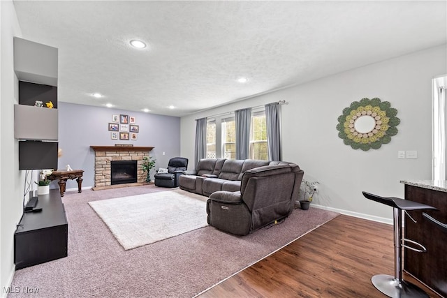 living room with recessed lighting, dark wood-type flooring, a fireplace, baseboards, and a textured ceiling
