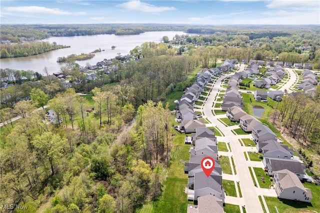aerial perspective of suburban area with a nearby body of water and a heavily wooded area