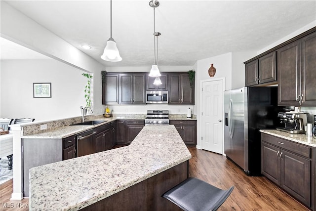 kitchen with stainless steel appliances, a sink, dark brown cabinetry, dark wood-style floors, and recessed lighting