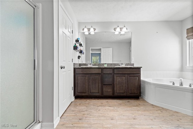 full bathroom with a garden tub, double vanity, wood finished floors, and a stall shower