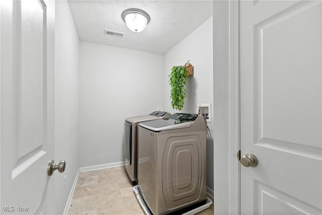 washroom featuring washer and dryer, baseboards, and a textured ceiling
