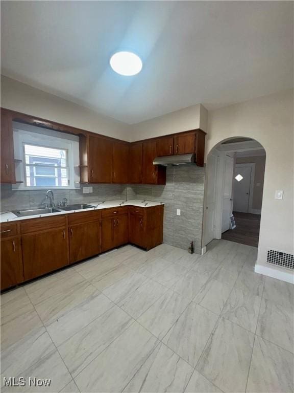 510 Parkcliffe Ave, Youngstown, OH 44511 - kitchen with a sink, arched walkways, light countertops, under cabinet range hood, and backsplash