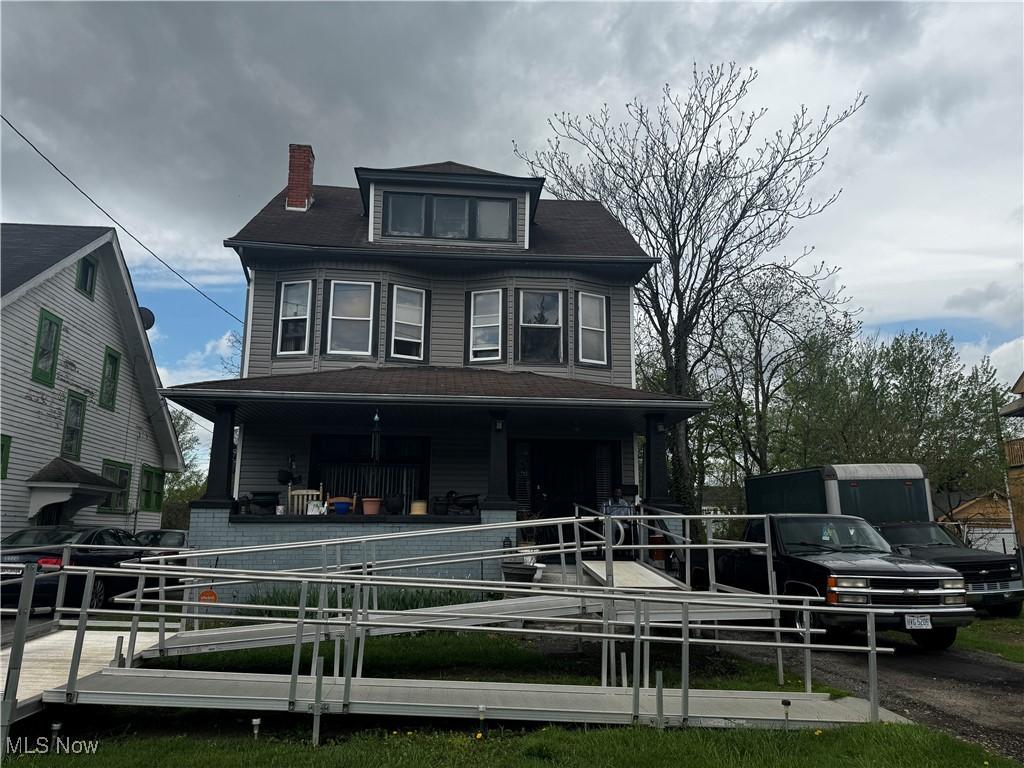 back of house featuring a porch and a chimney