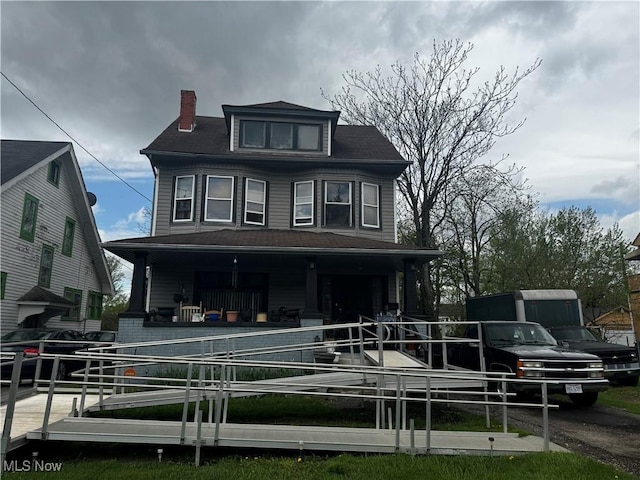 back of house featuring a porch and a chimney
