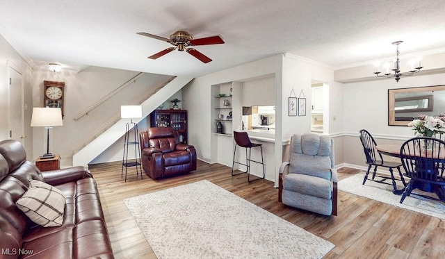 living area with a chandelier, wood finished floors, built in shelves, stairway, and ornamental molding