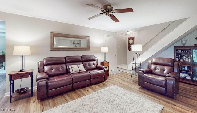 living area with a ceiling fan, stairway, wood finished floors, and baseboards