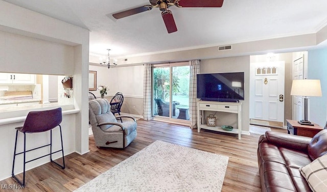 living area with wood finished floors, crown molding, a chandelier, ceiling fan, and baseboards