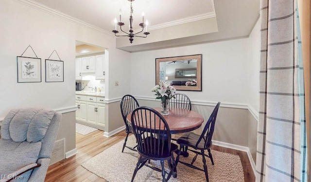 dining room featuring light wood-style floors, a chandelier, and crown molding
