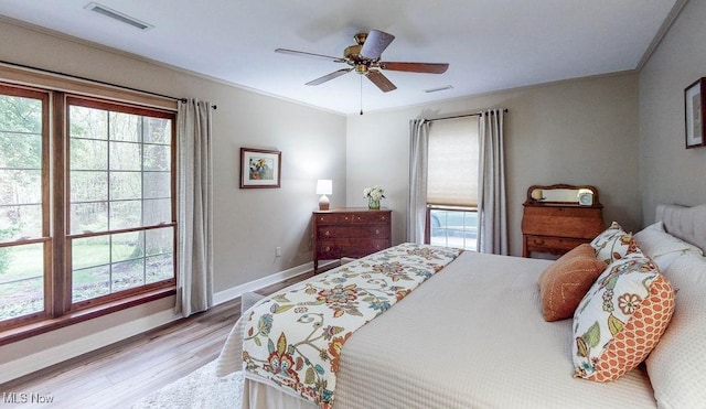 bedroom with multiple windows, wood finished floors, baseboards, and ceiling fan