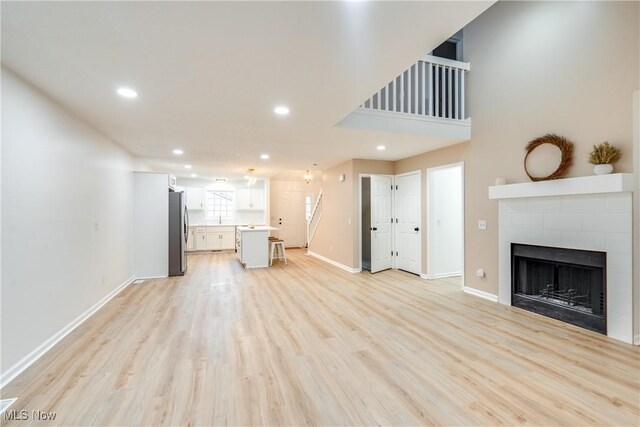 2875 Sherwood Ave NW, Massillon, OH 44646 - unfurnished living room with a tiled fireplace, baseboards, light wood-style floors, and recessed lighting