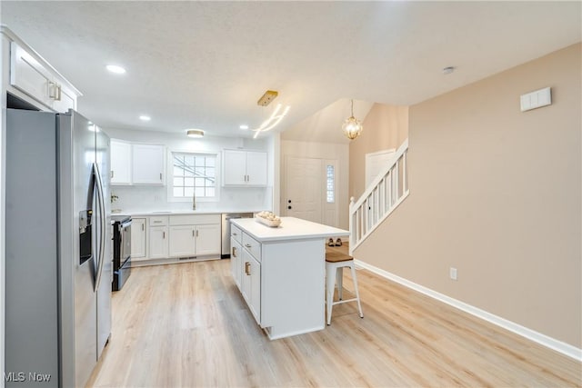 2875 Sherwood Ave NW, Massillon, OH 44646 - kitchen with stainless steel appliances, a sink, light wood-style flooring, white cabinetry, and a breakfast bar