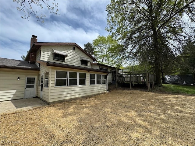 back of house with a wooden deck and a chimney