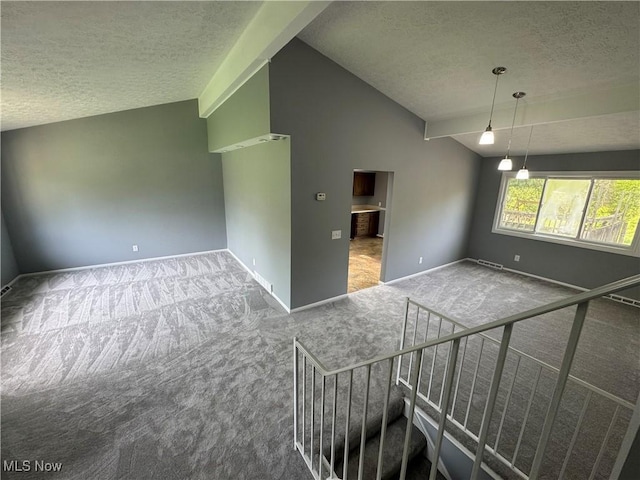 carpeted empty room with a textured ceiling, vaulted ceiling, and baseboards
