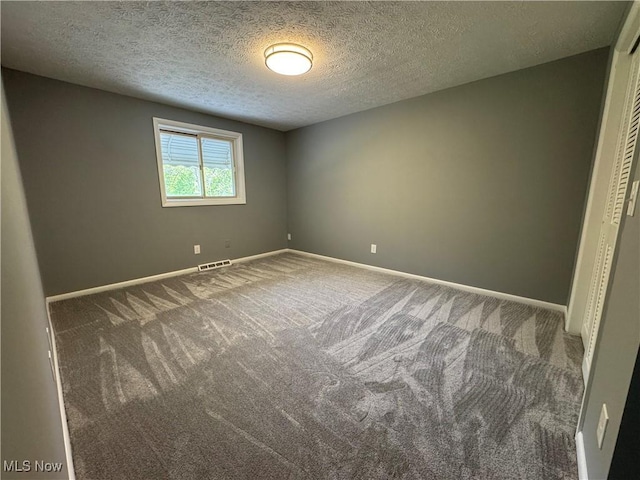 carpeted empty room featuring baseboards and a textured ceiling