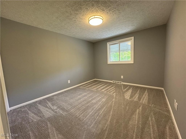 carpeted spare room featuring a textured ceiling and baseboards