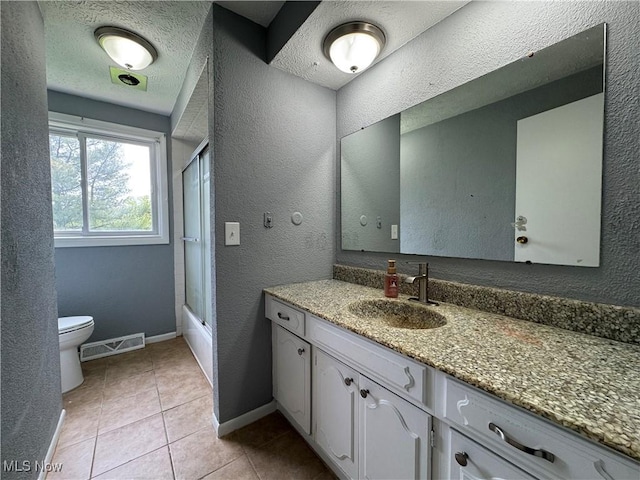 bathroom featuring toilet, vanity, a textured wall, baseboards, and tile patterned floors