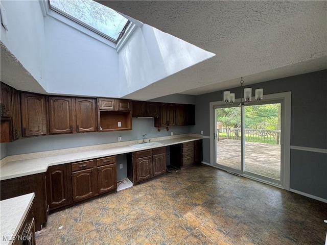 kitchen featuring a skylight, stone finish flooring, dark brown cabinets, baseboards, and a textured ceiling