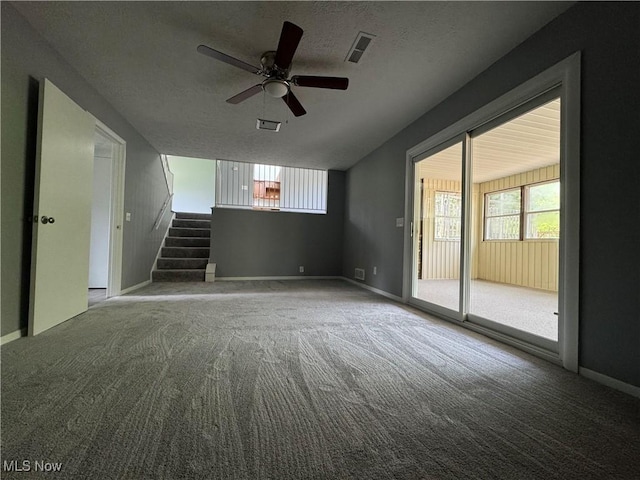 unfurnished living room with carpet floors, stairs, a textured ceiling, and ceiling fan