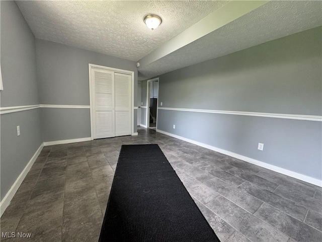 spare room featuring a textured ceiling and baseboards