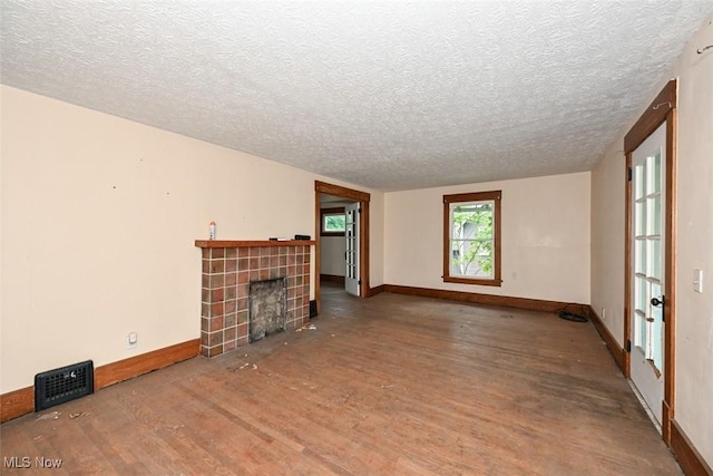 1324-1326 Shorb Ave NW, Canton, OH 44703 - unfurnished living room with wood finished floors, a textured ceiling, a tiled fireplace, and baseboards