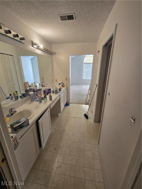 bathroom with a textured ceiling, vanity, and tile patterned floors