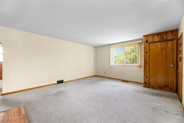 unfurnished room featuring baseboards and light carpet