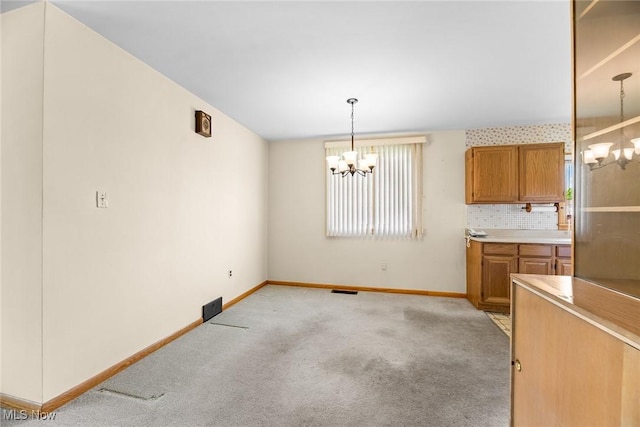 unfurnished dining area with a chandelier, baseboards, and light carpet