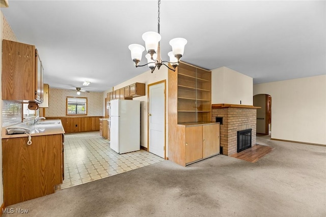 kitchen with freestanding refrigerator, arched walkways, a chandelier, a fireplace, and light colored carpet