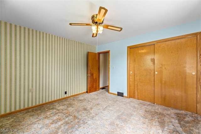 unfurnished bedroom with a closet, carpet flooring, baseboards, and a ceiling fan