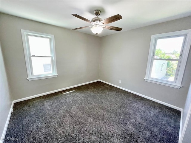 unfurnished room with dark colored carpet, a ceiling fan, and baseboards