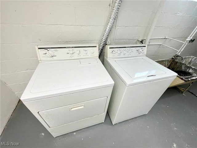 clothes washing area featuring washer and dryer and concrete block wall
