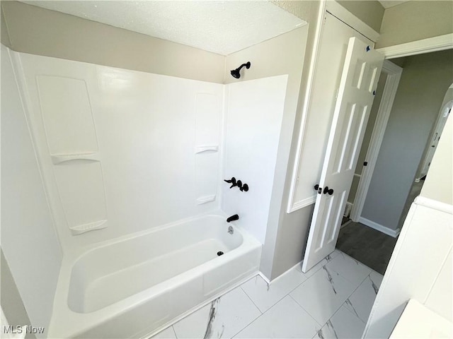 bathroom with marble finish flooring, baseboards, and shower / tub combination