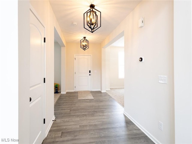 entryway featuring a chandelier, baseboards, and dark wood finished floors