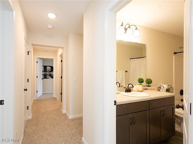 hall with a sink, light carpet, and baseboards