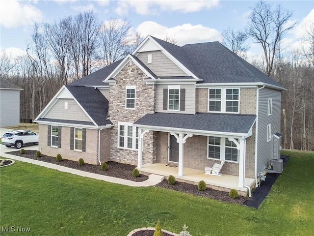 view of front of home featuring covered porch, a shingled roof, central AC, a front yard, and stone siding