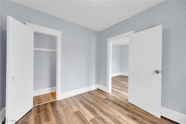 2040 W 103rd St, Cleveland, OH 44102 - unfurnished bedroom with wood finished floors, a textured ceiling, baseboards, and a closet