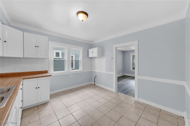 2040 W 103rd St, Cleveland, OH 44102 - kitchen with light tile patterned floors, white cabinetry, backsplash, and baseboards